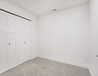 a bedroom with two closets and a carpeted floor at Meadowbrooke Apartment Homes, Michigan