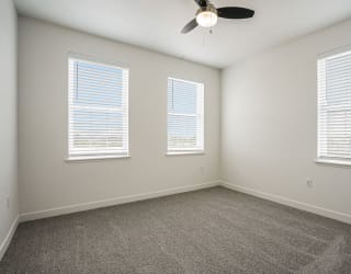 a bedroom with three windows and a ceiling fan at Meadowbrooke Apartment Homes, Grand Rapids, Michigan