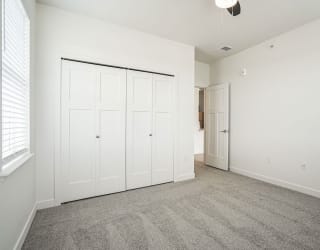 a bedroom with white walls and carpet and a door to a closet at Meadowbrooke Apartment Homes, Grand Rapids, MI