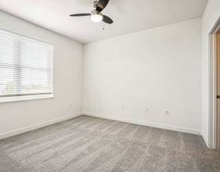 an empty living room with a window and a ceiling fan at Meadowbrooke Apartment Homes, Grand Rapids