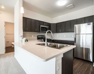 a kitchen with a sink and a stainless steel refrigerator at Meadowbrooke Apartment Homes, Grand Rapids, Michigan