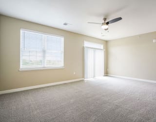 an empty living room with a ceiling fan and a window at Meadowbrooke Apartment Homes, Grand Rapids, Michigan