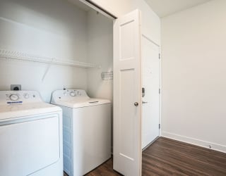 a white laundry room with two washes and a dryer at Meadowbrooke Apartment Homes, Michigan