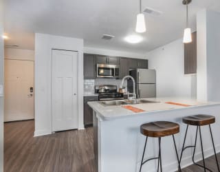 a kitchen with a counter top with two stools at Meadowbrooke Apartment Homes, Grand Rapids, MI