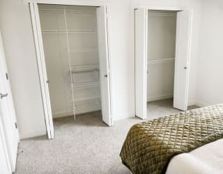 a bedroom with closet doors and a bed at Meadowbrooke Apartment Homes, Michigan