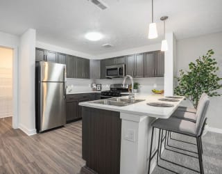 a kitchen with a island and a stainless steel refrigerator at Meadowbrooke Apartment Homes, Grand Rapids