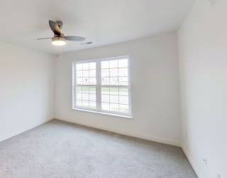 an empty living room with a window and a ceiling fan at Meadowbrooke Apartment Homes, Michigan