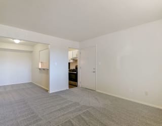 an empty living room with a door to the kitchen at Old Monterey Apartments, Springfield