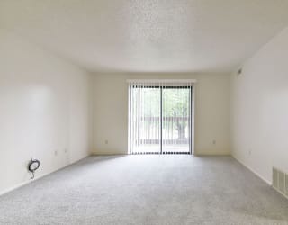 an empty living room with a sliding glass door to a balcony at Old Monterey Apartments, Springfield