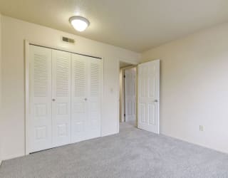 an empty living room with white doors and a door to a closet at Old Monterey Apartments, Springfield, MO