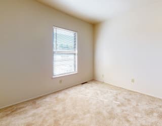 an empty bedroom with a window and carpeting at Mount Royal Townhomes, Kalamazoo, MI