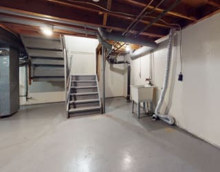 an empty basement with a staircase and a sink at Mount Royal Townhomes, Kalamazoo, 49009