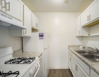 a kitchen with white cabinets and appliances at Newport Village Apartments, Portage, MI