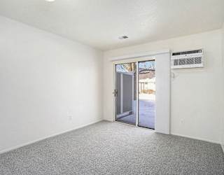 a bedroom with a slider to a semi private patio at Newport Village Apartments, Portage, MI