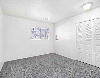 An upgraded bedroom with a window and large closet at Newport Village Apartments, Portage, MI
