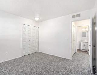 A spacious bedroom with plush carpet and a closet at Newport Village Apartments, Portage, MI