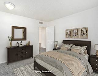 A bedroom with a bed, dresser, and mirror at Newport Village Apartments, Portage, MI