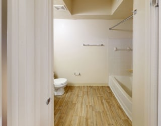 a renovated bathroom with a toilet and a tub at North Pointe Apartments in Elkhart, IN
