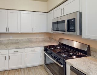 a kitchen with white cabinets and a stove and a microwave at North Pointe Apartments, Elkhart, IN
