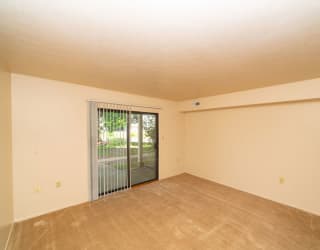 an empty living room with a sliding glass door to a patio at North Pointe Apartments, Elkhart, IN