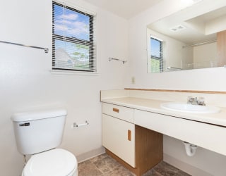 a bathroom with a toilet sink and a mirror  at Oak Shores Apartments, Oak Creek, WI, 53154