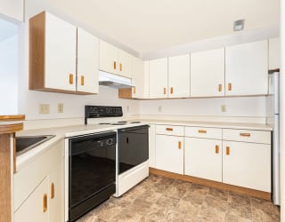 a kitchen with white cabinets and a black stove and oven  at Oak Shores Apartments, Wisconsin, 53154