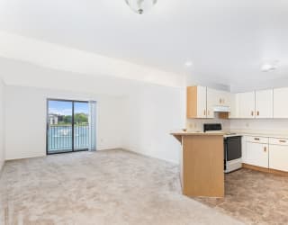 an empty living room and kitchen with a door to a balcony  at Oak Shores Apartments, Oak Creek, Wisconsin