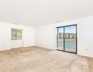 an empty living room with a sliding glass door to a balcony  at Oak Shores Apartments, Oak Creek, WI