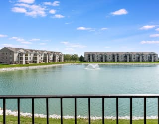 a pond with a fountain in front of an apartment building  at Oak Shores Apartments, Oak Creek, WI, 53154