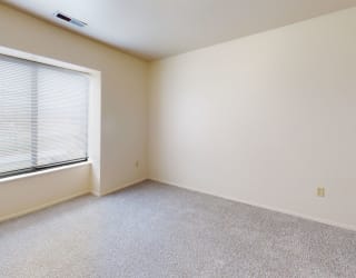 an empty bedroom with a large window and carpeting  at Oak Shores Apartments, Oak Creek, 53154