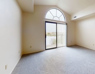 an empty living room with a glass door to a balcony  at Oak Shores Apartments, Oak Creek