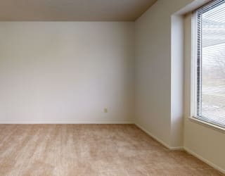 an empty room with a large window and carpeting at Pine Knoll Apartments, Battle Creek, 49014