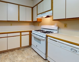 a kitchen with white appliances and white cabinets at Pine Knoll Apartments, Battle Creek, MI, 49014