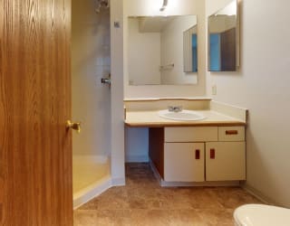 a bathroom with a toilet sink and a mirror at Pine Knoll Apartments, Battle Creek, MI, 49014