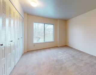 an empty living room with a window and a closet at Pine Knoll Apartments, Battle Creek, MI