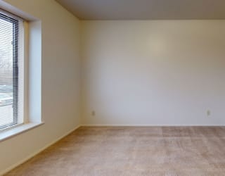 a empty room with a large window and carpet  at Pine Knoll Apartments, Battle Creek, MI
