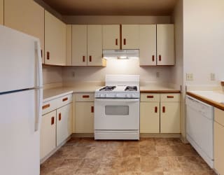 a kitchen with white appliances and white cabinets at Pine Knoll Apartments, Battle Creek