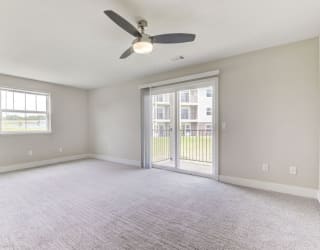 an empty living room with a ceiling fan and a door to a balcony  at Signature Pointe Apartment Homes, Alabama, 35611