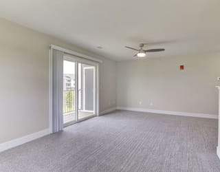 an empty living room with a ceiling fan and a door to a balcony  at Signature Pointe Apartment Homes, Alabama