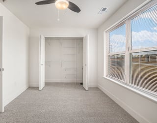 a bedroom with a large window and a ceiling fan  at Signature Pointe Apartment Homes, Alabama