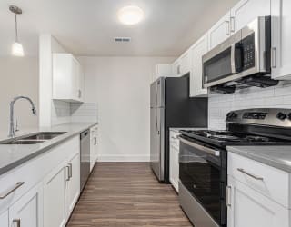 a modern kitchen with stainless steel appliances and white cabinets  at Signature Pointe Apartment Homes, Athens, AL