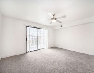 an empty living room with a ceiling fan and a slider to a private balcony at Stoney Pointe Apartment Homes, Wichita, 67226