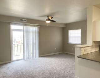 end living room with a ceiling fan and a slider to a balcony at Stoney Pointe Apartment Homes, Wichita, KS