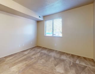 an empty living room with a white door and a window at Swiss Valley Apartments, Wyoming, MI