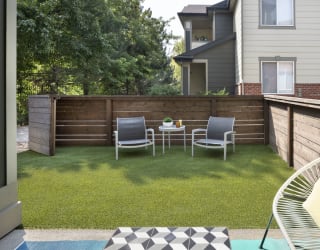 a backyard with a wooden fence and a patio with two chairs and a table