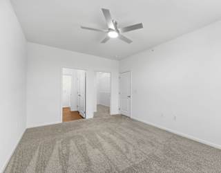 A room with a ceiling fan and carpeted floor.