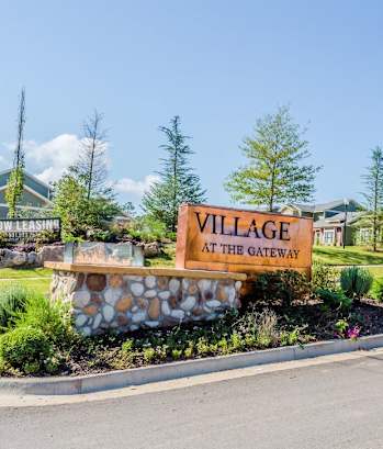 a sign that says village at the gateway with houses in the background