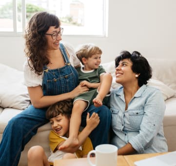 a mother and father sit on a couch with their children