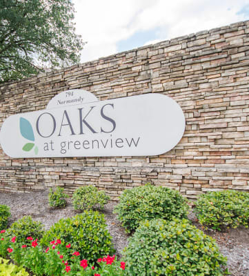 a sign that says oaks at greenview in front of a brick wall