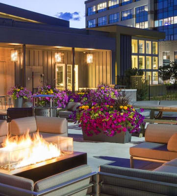 a patio with couches and a fire pit in front of a building